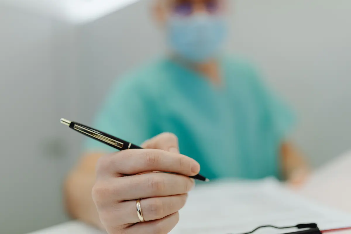 A clinician's hands over notes during a consultation